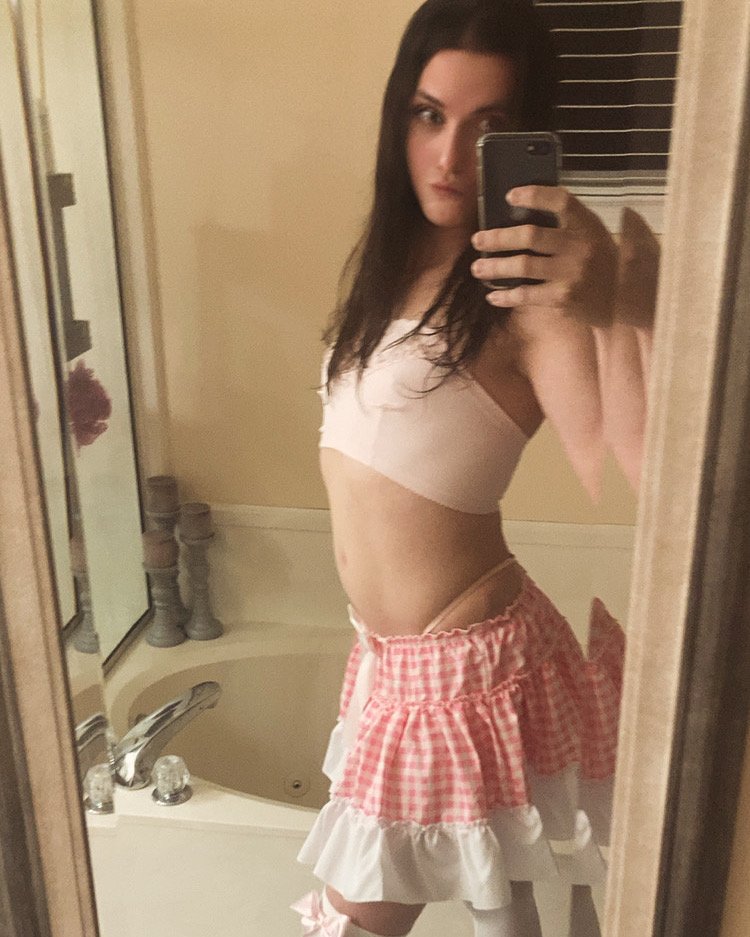 Zoe Simpson wearing a pale pink top and a pink gingham skirt with white ruffles in a mirror selfie
